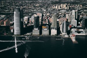 Aerial view of Jersey City, NJ waterfront skyline with Goldman Sachs tower, Hudson River, and boat wake trails